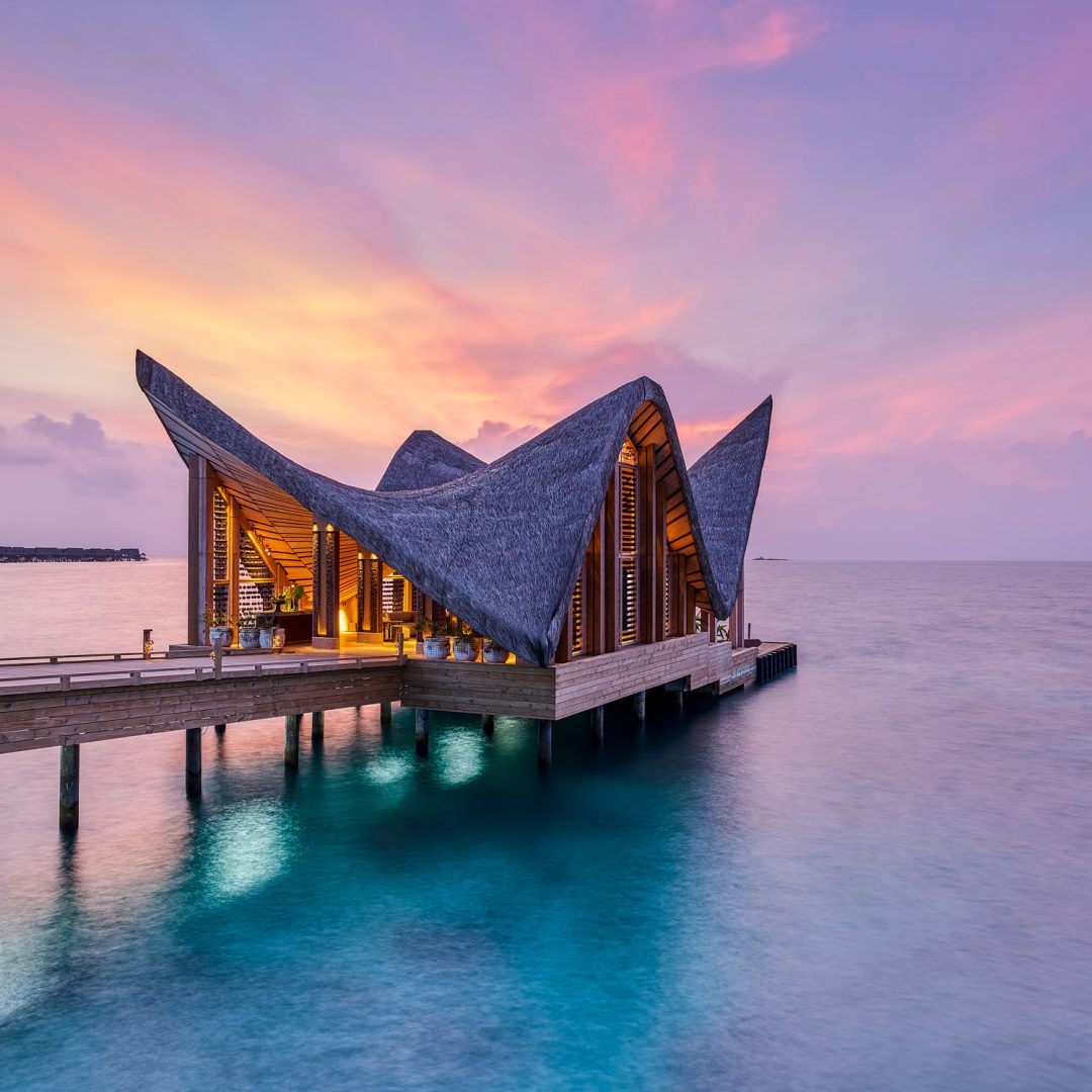 Sonnenuntergang hinter Wasserbungalow und Meer auf den Malediven